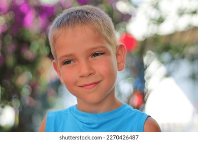 A shy fashionable schoolboy in the summer bowed his head and thinks about something. A large portrait on a summer floral blurred background. - Shutterstock ID 2270426487