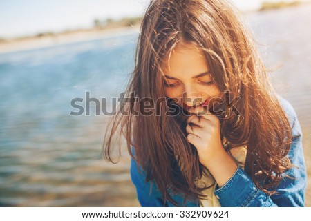 Shy girl sanding looking down. Cute teenage girl being shy on lake background. Film effect.