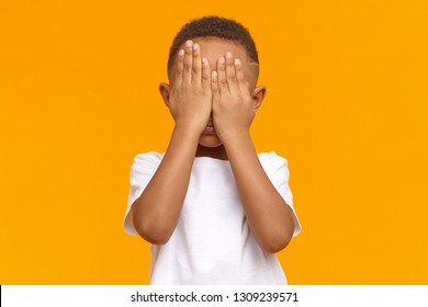 Shy Little Boy Feeling Ashamed Because Of His Bad Behavior, Crying, Not Showing His Tears. Isolated Shot Of Unrecognizable Male Kid With Hands On His Face, Being Afraid Of Scary Movie. Body Language