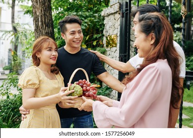 Shy Pretty Vietnamese Woman Giving Basket Of Fruits To Parents Of Her Boyfriend When Visiting Them For The First Time