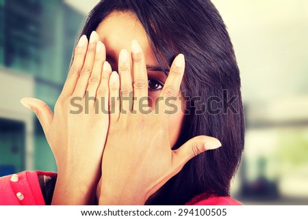Shy woman peeking through covered face