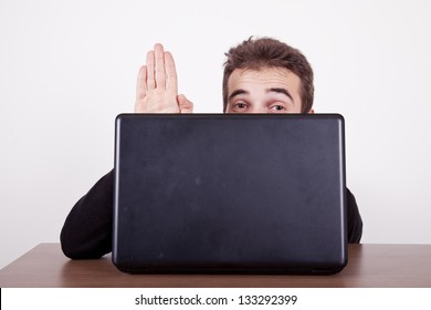 Shy Young Man Waving Hello From Behind A Laptop Screen