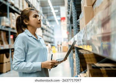 sian warehouse worker checking inventory using laptop computer for stock management and logistics control in modern storage facility, digital transformation in supply chain business.