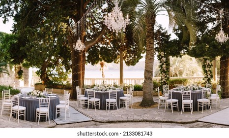Sibenik, Croatia - 05.06.17: Wedding dinner table reception. Round banquet tables for guests with gray tablecloth. Floral arrangement of roses in center of the table.