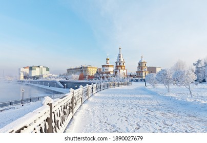 Siberian city of Irkutsk on frosty winter day. View from the snow-covered lower embankment of the Angara River to the Epiphany Cathedral and the monument to the founders of the city. Winter cityscape