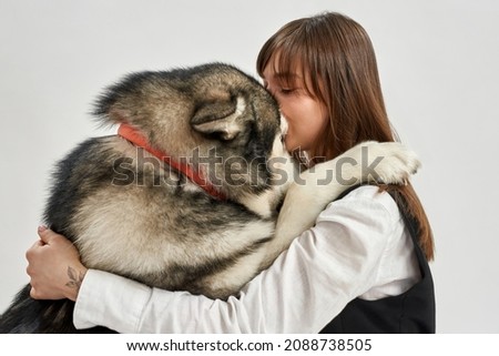 Siberian Husky dog and caucasian woman hug each other. Closeness. Concept of relationship between human and animal. Owner and pet friendship. Side view of girl and dog on white background in studio