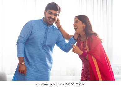 Sibling lovingly pulling each other's ear while celebrating Raksha Bandhan - Powered by Shutterstock