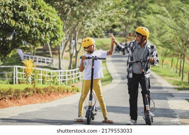 Sibling on vacation doing high five before driving electric scooter at the street park. Youth Leisure Family Concept. - Powered by Shutterstock