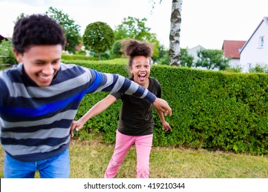 Siblings, Black Boy And Girl, Playing In Garden