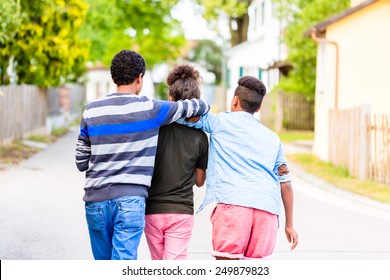 Siblings, black girl and two boys, walking down the village road