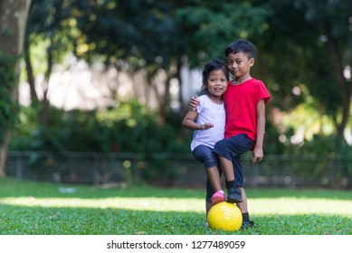 Siblings - Boy And Girl - Playing Football At A Park. South East Asian, Muslim Children. Happy Expression