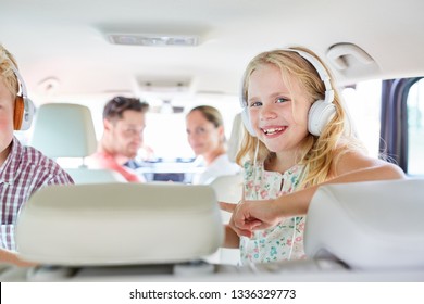 Siblings Children In The Back Seat In The Car On Family Vacation With Headphones