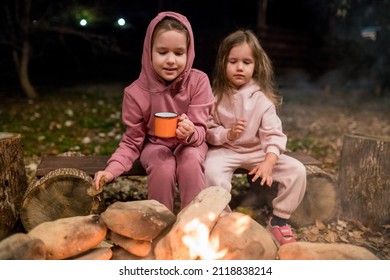 Siblings Having Fun Around The Bonfire. Girls Warming And Telling Campfire Stories, Legends. Exciting Camping Activities For Kids And Family Getaway. Selective Focus