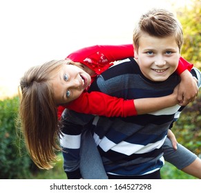 Siblings having fun - boy carrying his sister on his back.