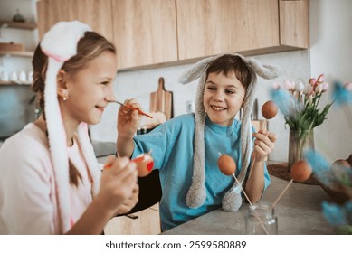 Siblings having fun while paiting eggs for easter.
