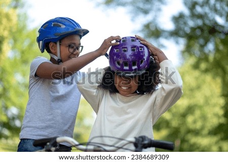 Siblings helping each other to put on a protective hemlet