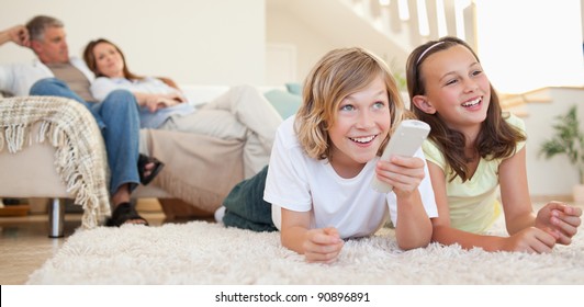 Siblings lying on the floor watching tv together