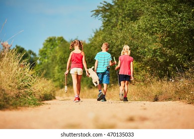 Siblings In Nature. Two Girls And One Boy Holding Toys And Go Play.