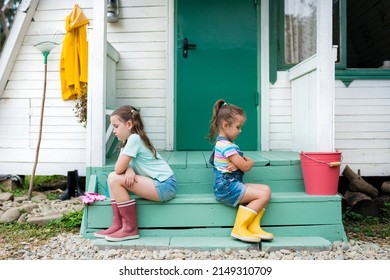 Siblings sitting  back to back avoid talking . Kids  quarreling and sulking  each other on porch at backyard against house. Life in the suburbs.