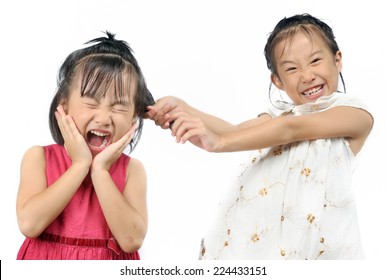 Siblings Teasing, Asian Little Girl Pulling Her Sister's Hair In The White Background