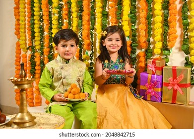 Siblings In Tradional Clothes Holding Diwali Mithai And Diya In Hand On The Occasion Of Diwali Festival