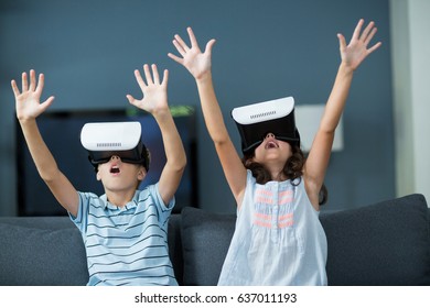 Siblings using virtual reality headset in living room at home