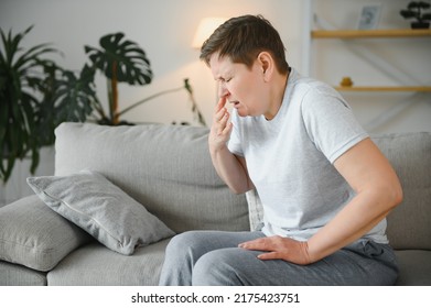 Sick Adult Woman Coughing Covering Mouth With Tissue Sitting On A Couch At Home