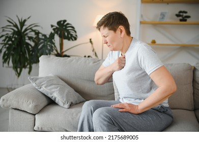 Sick Adult Woman Coughing Covering Mouth With Tissue Sitting On A Couch At Home