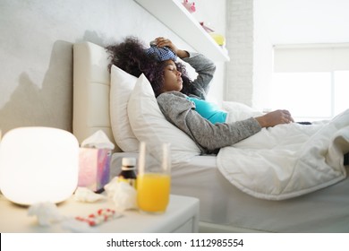 Sick African American Girl With Flu At Home, Ill Young Black Woman With Fever And Ice Bag On Head, Resting In Bed.