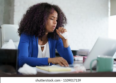 Sick african american girl working from home office. Ill young black woman with cold, working on laptop computer, coughing and sneezing. - Powered by Shutterstock