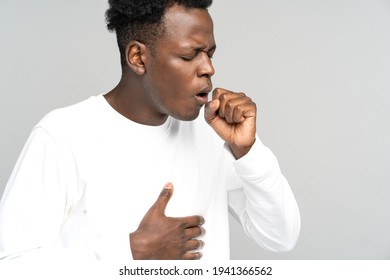 Sick African American Man Strongly Coughing. Black Man Feeling Unwell, Suffered From Asthma, Flu, Allergy, Bronchitis, Tuberculosis, Virus, Touching Her Chest, Isolated On Studio Grey White Background