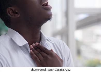 Sick African Man With Sore Throat; Portrait Of Ill Black Man Suffering From Sore Throat Due To Cold, Flu, Allergy, Polluted Air, Dust, Smog; Air Pollution Sickness Concept; African Man Model