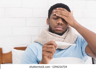 Sick African-american Man Having Fever, Measuring Body Temperature With Thermometer, Touching Forehead In Bed, Copy Space