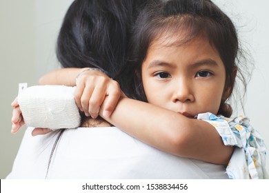 Sick Asian Child Girl Who Have IV Solution Bandaged Hugging Her Mother With Love In The Hospital