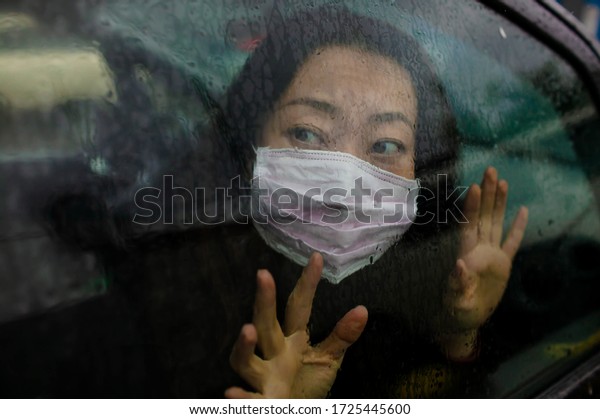 Sick Asian girl in Car Wearing Protective Face\
Mask Coughs Sneeze\
Covid-19