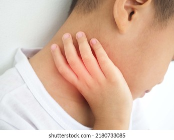 Sick Asian Kid Touching His Painful Neck, Sore Throat And Flu, Throat Infection On White Background. Closeup Photo, Blurred.