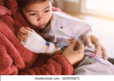 Sick Asian Little Child Girl Who Have IV Solution Bandaged Hugging Her Mother With Love In The Hospital