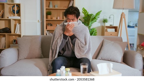 Sick Asian Man Has Running Nose And Feels Uncomfortable On Sofa In Living Room At Home