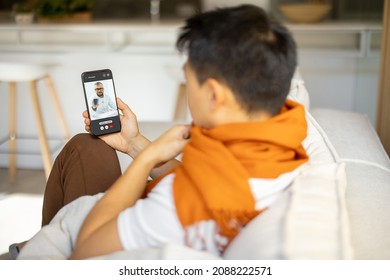 Sick asian man having video call with his doctor on smartphone. Concept of online medicine and health care. Idea of medical mobile app. Blurred image of male person with scarf on neck at home - Powered by Shutterstock