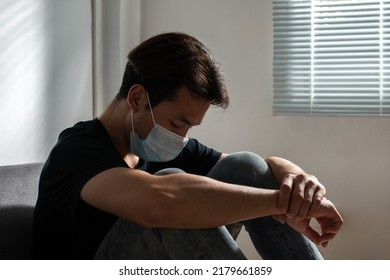 Sick Asian Man Wear Mask During Covid. Crisis Virus Scared Depressed Tired Hopeless Anxiety Frustrated Lonely Male Human. Headache Stressed Overwhelmed Depression Patient Sit Worried Covid Virus.