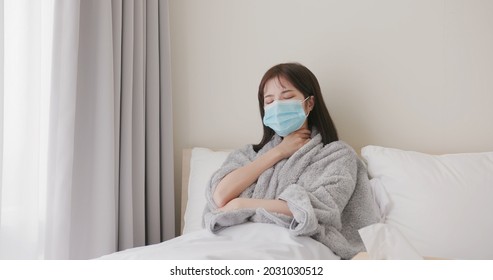 sick asian woman wears potective face mask due to getting a fever and feeling uncomfortable on bed at home - Powered by Shutterstock