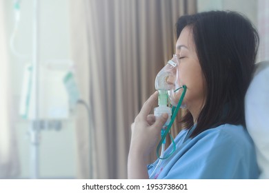 Sick beautiful female in blue cloth hold nasal mask with respiratory problem in hospital room. Asian woman patient inhalation therapy by the mask of inhaler with soft stream smoke from bronchodilator. - Powered by Shutterstock