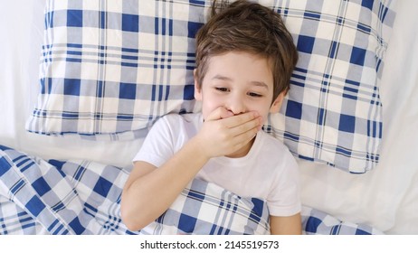 Sick Boy Touching His Painful Neck, Sore Throat And Flu, Throat Infection. Toddler Boy Is Lying In Bed And Blowing Nose Into Tissue Paper At Home. Allergy, Flu