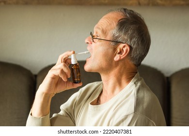 Sick Caucasian Senior Man With Open Mouth Using A Throat Spray Against A Dry Cough, Side View. Health Care Concept.