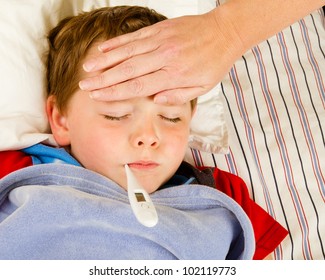 Sick Child Boy Being Checked For Fever And Illness While Resting In Bed