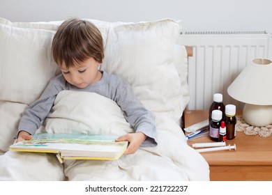 Sick Child Boy Lying In Bed With A Fever, Resting Reading A Book