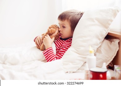 Sick Child Boy Lying In Bed With A Fever, Holding Terry Bear With Band Aid, Resting