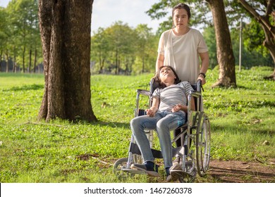 Sick Child Girl With Cerebral Palsy In Wheelchair In Outdoor Park, Daughter Suffering From Seizures,illness With Epilepsy,asian Mother Or Caregiver Care Of Girl Patient,brain,intellectual Disability 