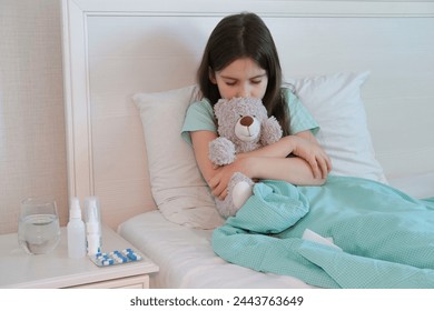 Sick child sick at home, lying in bed with teddy bear. Sad look of girl. flu, acute respiratory viral infections, colds. Children's healthcare. - Powered by Shutterstock