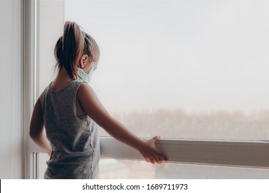 Sick Child Little Girls Look At The Window With With A Protective Mask On His Face. Retro Tinted. Little Girl In Hospital. Child Girl Wearing A Protective Mask. Copy Space. Kid At Home In Isolation.  